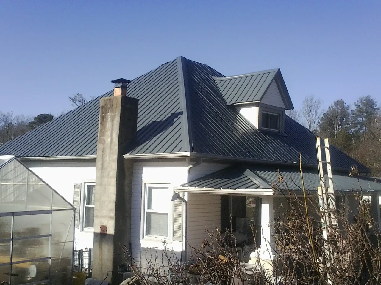 Dark blue standing seam metal roof on a white farmhouse with dormer — Slate & Tile Roof Repair by Roofing Brothers in Drayton