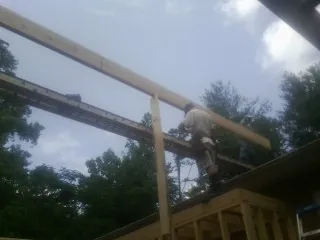 Carpenter setting a ridge beam over a new addition frame — Ice Dam Removal by Roofing Brothers in Drayton