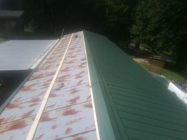 Old rusted panels beside newly installed green metal roofing — Wind Damage Roof Repair by Roofing Brothers in Drayton
