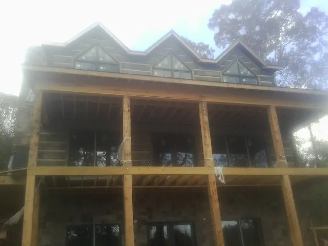 Dormers and porch framing on a large log home under construction — Roof Coating work by our crew in Drayton