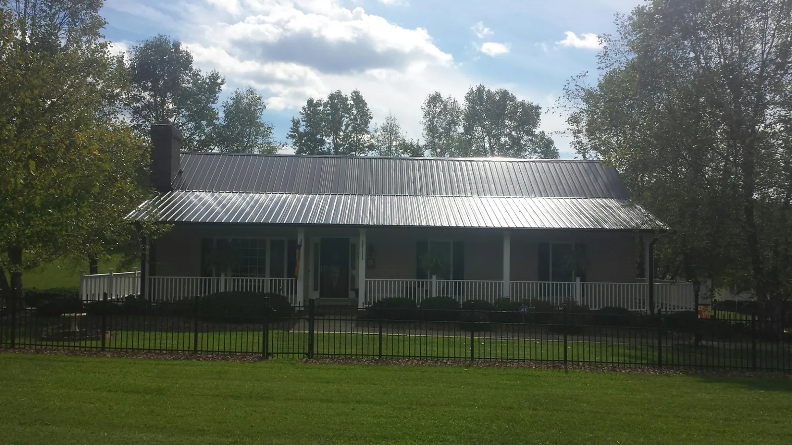 Gray metal roof on a brick ranch with a full width front porch — Gutter Guard Installation work by our crew in Drayton