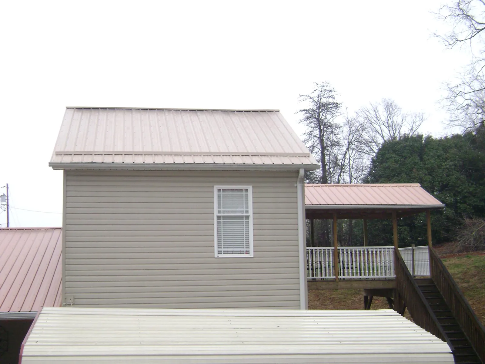 Tan metal roofs on a two story addition and attached porch, from a Roof Replacement job in Drayton